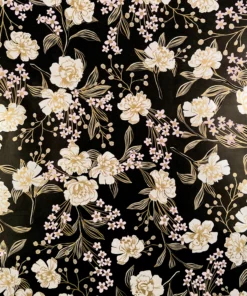 This image depicts an elegant and intricate floral pattern on a dark background. The design features large, luxurious white/cream and light pink flowers with delicate gold accents. The flowers are surrounded by lush, flowing leaves and stems. Smaller pink flowers, buds, and gold accents are scattered throughout. The combination of the dark background and the warm, luxurious tones of the flowers and foliage gives the design a sophisticated, refined, and opulent feel, making it well-suited for high-end or luxury gift wrapping, as well as events such as Mother’s Day and birthday throughout the year.